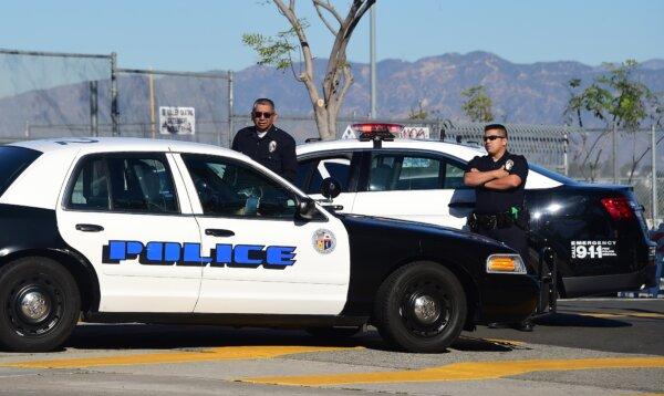 A police vehicle pulls up next to two officers standing at their vehicle outside a closed school near downtown Los Angeles on Dec. 15, 2015. (Frederic J. Brown/AFP via Getty Images)