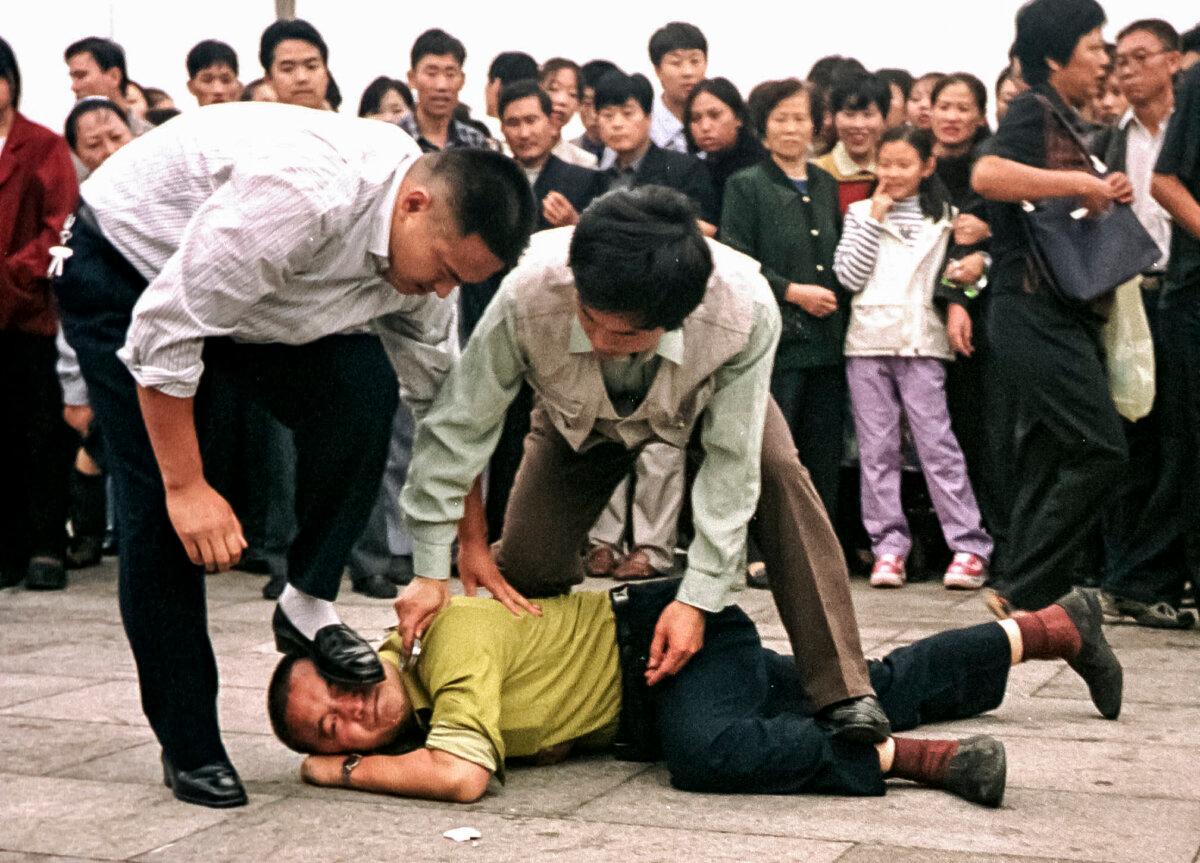 Police detain a Falun Gong practitioner as a crowd gathers around in Tiananmen Square in Beijing on Oct. 1, 2000. (Chien-Min Chung/AP Photo)