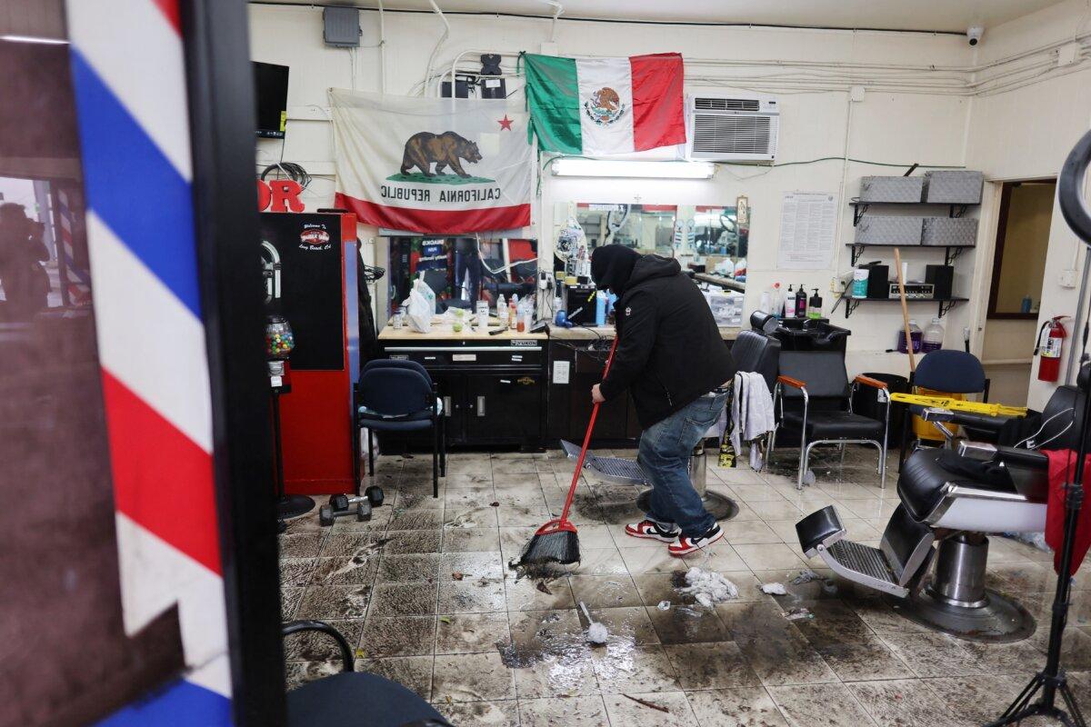 A man sweeps floodwater inside his barbershop during a rain storm in Long Beach, Calif., on Feb. 1, 2024. (David Swanson/AFP via Getty Images)