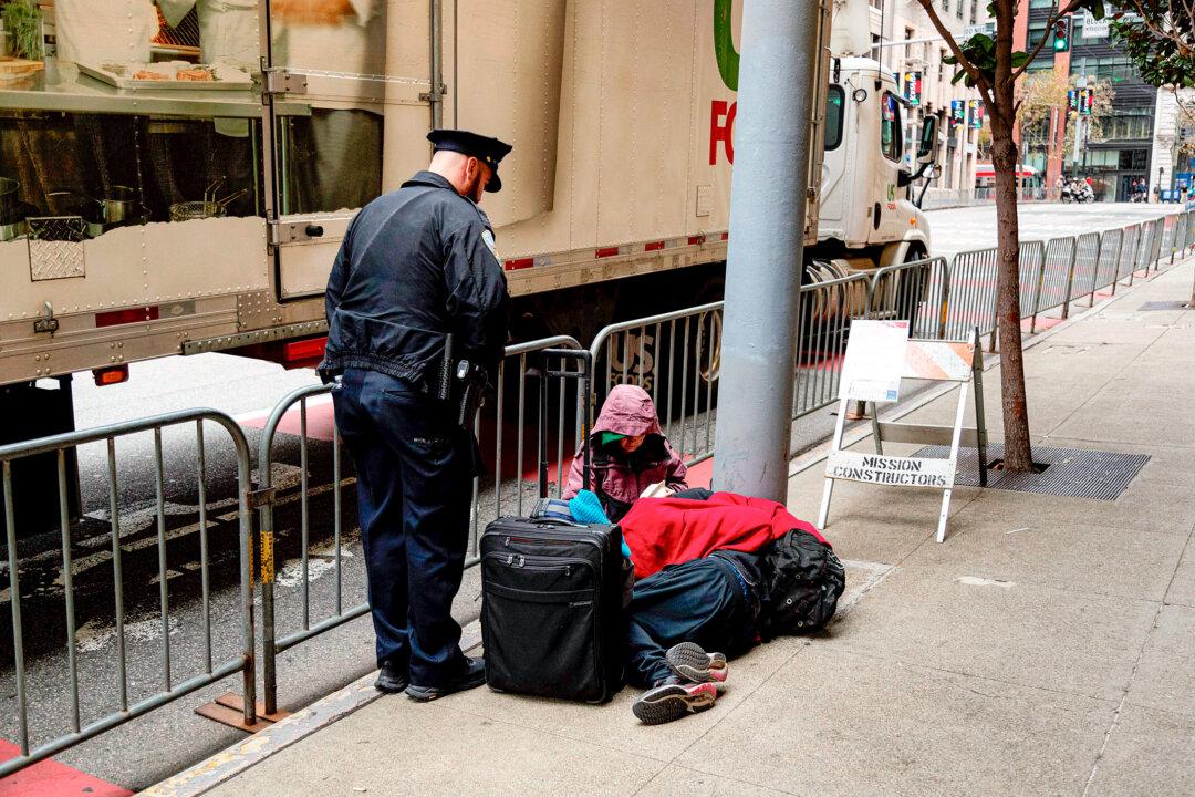 A San Francisco police officer asks two homeless people on the sidewalk to move off the street during the Asia-Pacific Economic Cooperation forum, in San Francisco on Nov. 14, 2023.