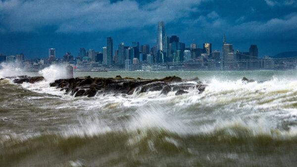 Waves crash over a breakwater in Alameda, Calif., with the San Francisco skyline in the background on Feb. 4, 2024. (Noah Berger/AP Photo)