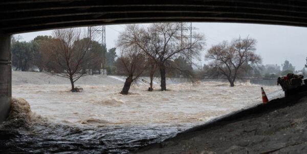 Water rages past a cart filled with items used by homeless people living along the Los Angeles River as the second and more powerful of two atmospheric river storms inundates Los Angeles bringing record rainfall and flooding, on Feb. 5, 2024. (Robyn Beck/AFP via Getty Images)
