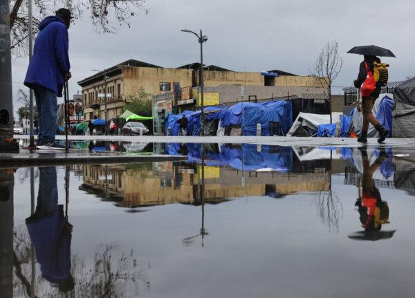 People gather near an encampment of homeless people in Skid Row as a powerful long-duration atmospheric river storm, the second in less than a week, continues to impact Southern California in Los Angeles on Feb. 6, 2024. (Mario Tama/Getty Images)