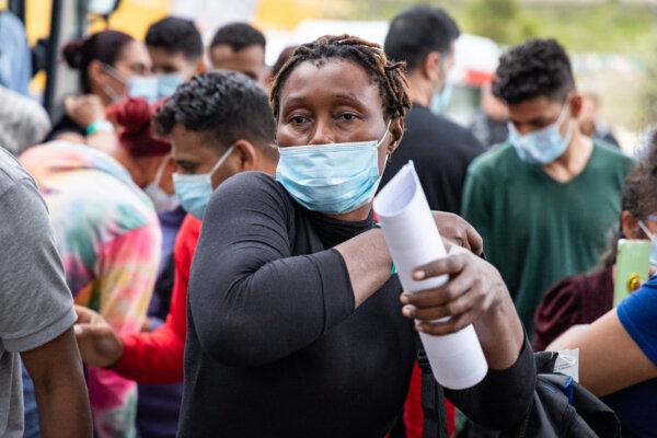 An illegal immigrant holds her processing paperwork after being dropped off by bus in San Ysidro, Calif., on Feb. 29, 2024. (John Fredricks/The Epoch Times)