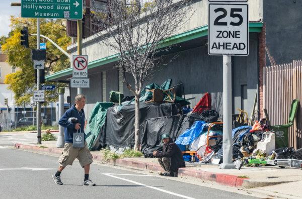 A man walks past a homeless encampment in Los Angeles on March 4, 2024. (John Fredricks/The Epoch Times)