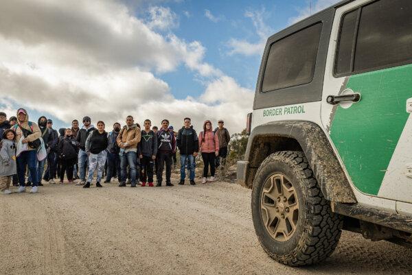 Illegal immigrants gather after crossing the U.S. border wall in Jacoumba, Calif., on Jan. 10, 2024. (John Fredricks/The Epoch Times)