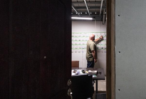 Cory Gautereaux looks through discarded ID cards found near the U.S. border wall in Pine Valley, Calif., on April 12, 2024. (John Fredricks/The Epoch Times)