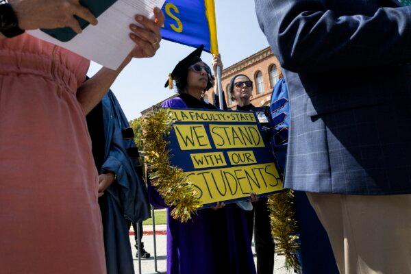 A demonstrator holds a poster showing support for student protesters near the pro-Palestinian encampment on the UCLA campus on May 1, 2024. (Etienne Laurent / AFP)