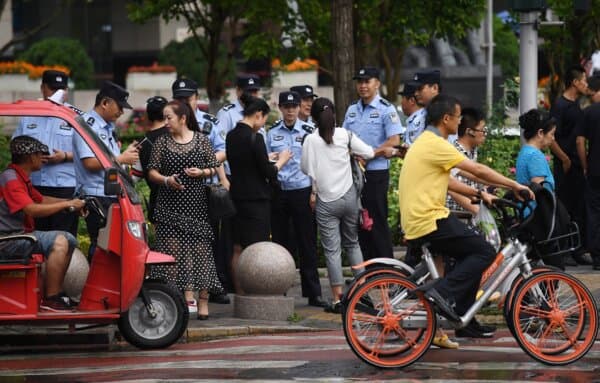 Police check the identification of passersby as they search for petitioners who planned to protest against losses sustained by peer-to-peer (P2P) lending platforms near China's Banking Regulatory Commission in Beijing on August 6, 2018. (Greg Baker/AFP via Getty Images)