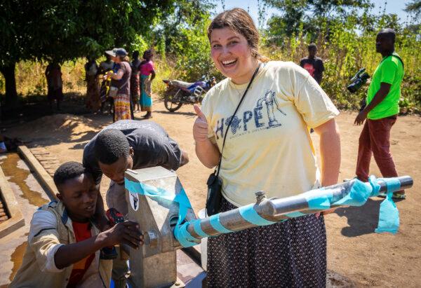Brittney Harris stands by a water well built by Water Wells for Africa in Southern Malawi on June 9, 2023. (John Fredricks/The Epoch Times)