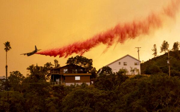 An airplane drops fire retardant over homes as flames from the LNU Lightning Complex fire rage through the Spanish Flat area of Napa, Calif., on Aug. 18, 2020. (Josh Edelson/AFP via Getty Images)