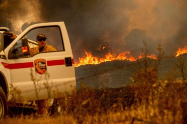 The Ranch fire, part of the Mendocino Complex Fire, crests a ridge as Battalion Chief Matt Sully directs firefighting operations on High Valley Road near Clearlake Oaks, Calif., on Aug. 5, 2018. (Noah Berger/AFP via Getty Images)