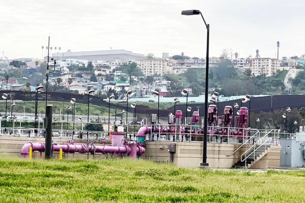 Purple pipes for reclaimed water at South Bay International Wastewater Treatment Plant in San Diego on Mar. 14, 2023. Seen in the background are the old border fence and houses in Tijuana, Mexico. (Jane Yang/The Epoch Times)