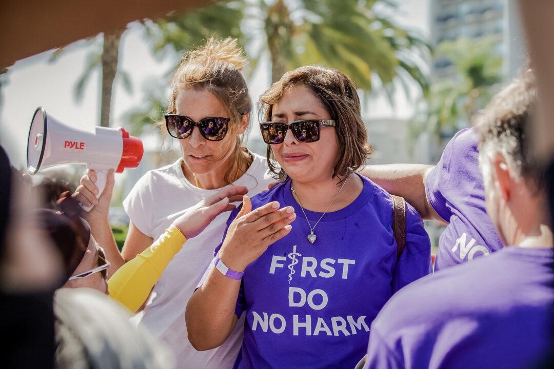 Erin Friday comforts Abigail Martinez (R), the mother of a transgender teen who committed suicide, while transgender activists block TV cameras from capturing her story, in Anaheim, Calif., on Oct. 8, 2022. (John Fredricks/The Epoch Times)