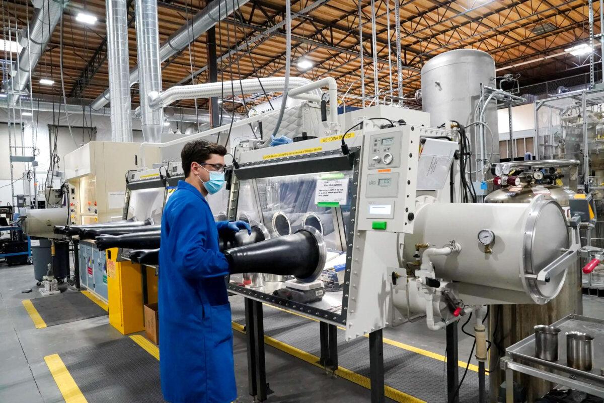 Test engineer Jacob Wilcox pulls his arm out of a glove box used for processing sodium at TerraPower, a company developing and building small nuclear reactors in Everett, Wash., on Jan. 13, 2022. (Elaine Thompson/AP Photo)