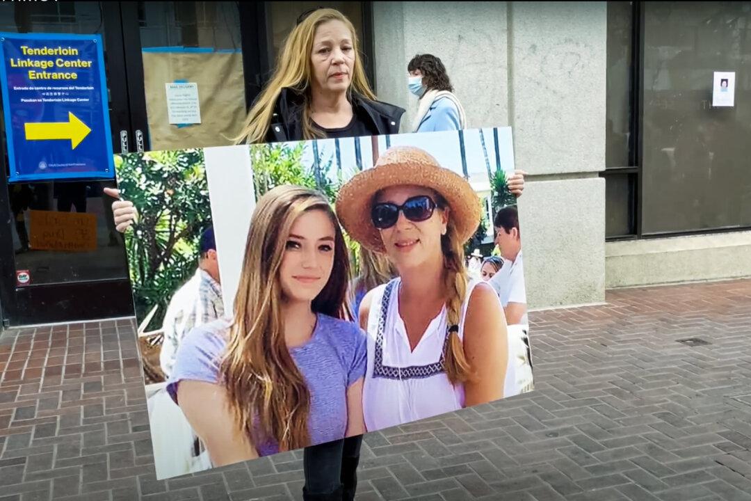 Gina McDonald holds a poster of herself and her daughter at a protest in front of the Tenderloin Linkage Center in San Francisco on Feb. 5, 2022. (Cynthia Cai/The Epoch Times)