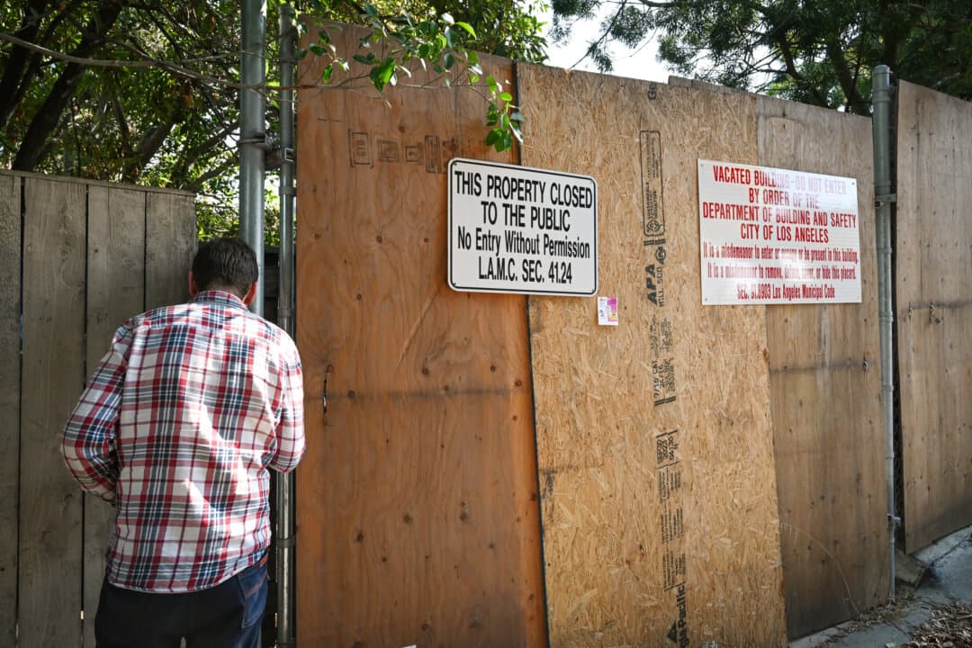 A man looks to get a view of an abandoned mansion covered in graffiti in the Hollywood Hills neighborhood of Los Angeles on Sept. 20, 2024. Neighbors said the house has been a refuge for squatters coming and going for over two years. (Robyn Beck/ AFP/AFP via Getty Images)