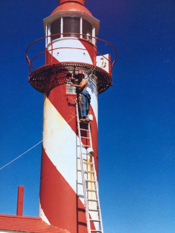 Barry Porter stands on a ladder at the Bacalhao Island lighthouse in Newfoundland and Labrador. (Courtesy of Barry Porter)