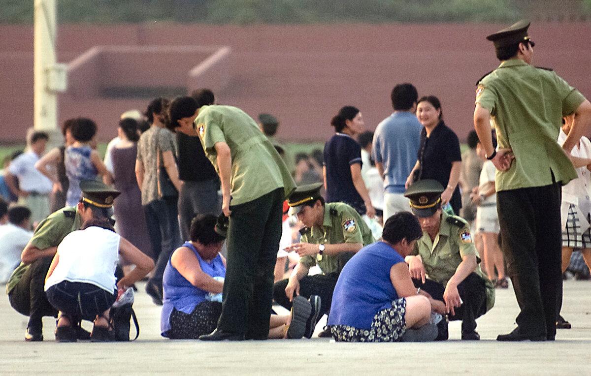 Chinese police swoop down upon several women they suspect of being Falun Gong practitioners, in Tiananmen Square in Beijing on July 23, 1999. (Stephen Shaver/AFP via Getty Images)
