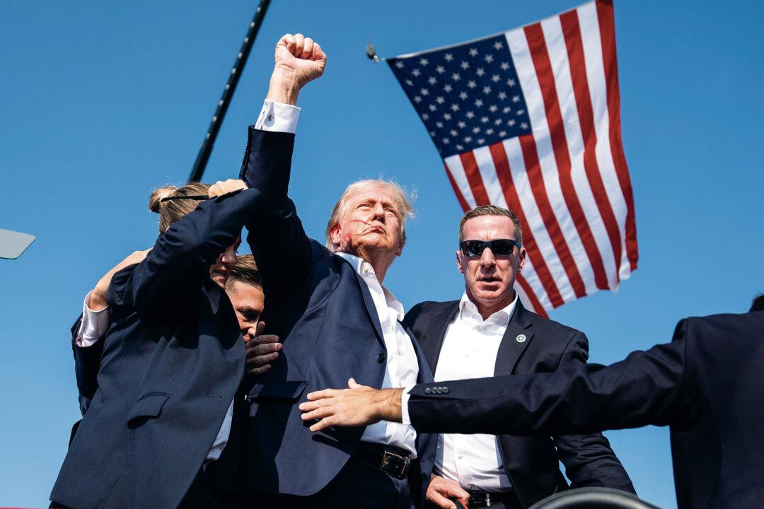 Republican presidential candidate former President Donald Trump raises his fist after being shot, while Secret Service agents surround him, at a campaign rally in Butler, Pa., on July 13, 2024. (Evan Vucci/AP Photo)