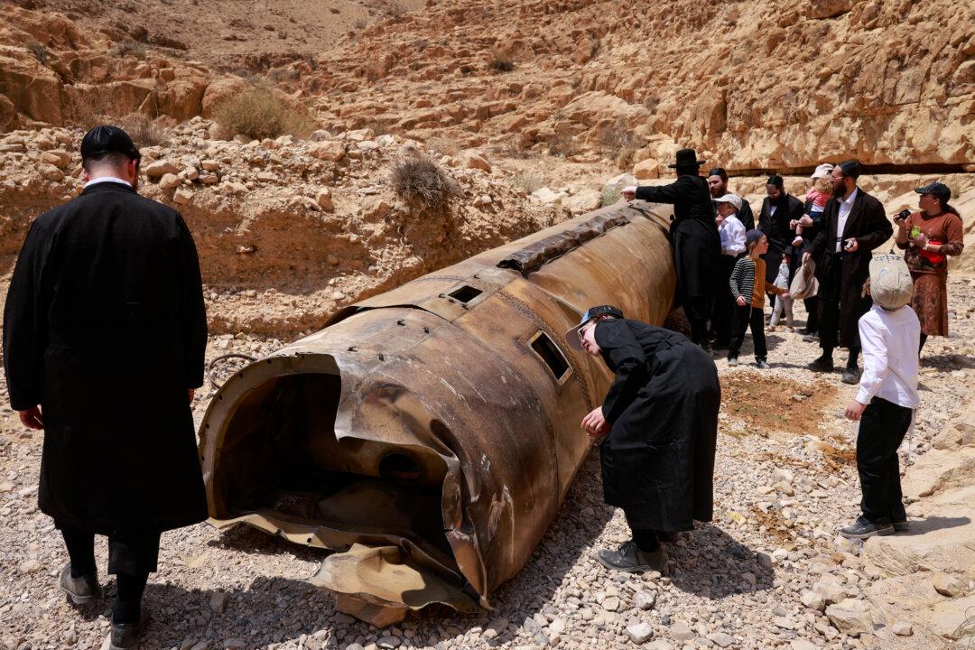 People gather around the remains of one of the ballistic missiles fired by Iran earlier in the month and intercepted by Israel, that landed in an open area of the Negev desert near the city of Arad, Israel, on April 30, 2024. (Menahem Kahana/AFP via Getty Images)