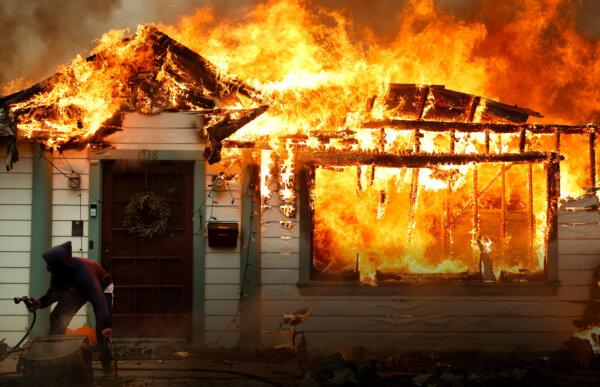 A person turns on a garden hose in an effort to save a neighboring home from catching fire during the Eaton Fire in Altadena, Calif., on Jan. 8, 2025. (Mario Tama/Getty Images)
