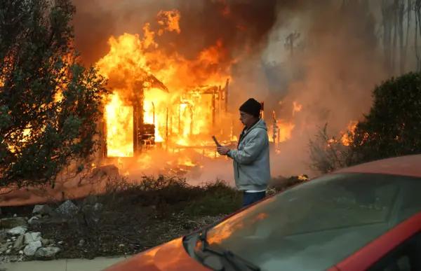 A person walks past a burning home during the Eaton Fire in Altadena, Calif., on Jan. 8, 2025. (Mario Tama/Getty Images)