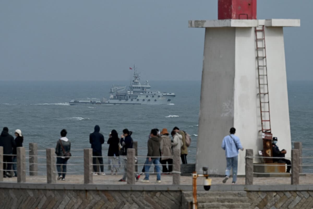 A Chinese navy tugboat sails in the Taiwan Strait, past tourists on Pingtan Island, the closest point to Taiwan, in Fujian Province, China, on April 7, 2023. (Greg Baker/AFP via Getty Images)