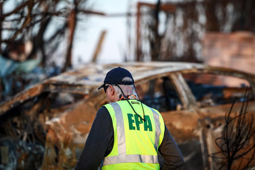 (Top) Vehicles burned in the Eaton Fire are marked “NOT EV” as EPA hazardous materials disposal, including lithium electric vehicle batteries, ramp up in Altadena, Calif., on Jan. 31, 2025. (Bottom) An EPA representative works in a residential area damaged by the Palisades Fire in Pacific Palisades, Calif., on Jan. 28, 2025. (Mario Tama/Getty Images)