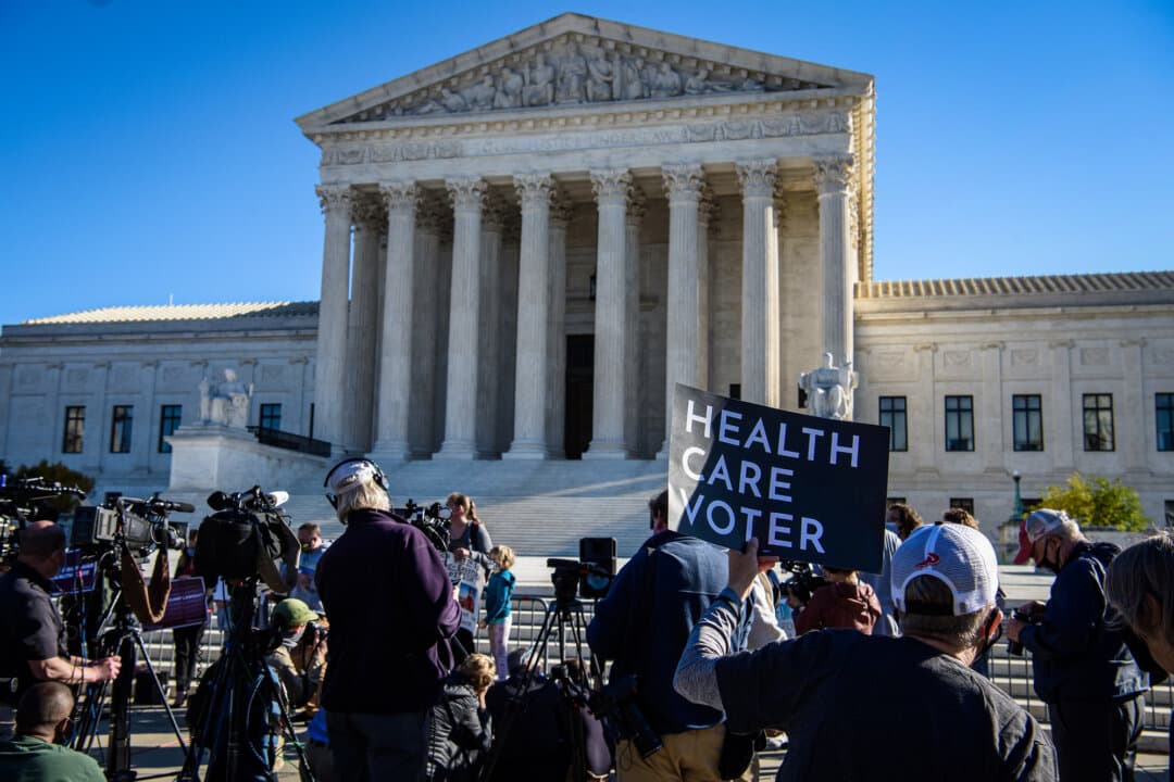 A demonstrator holds a sign outside the high court in Washington as the U.S. Supreme Court opens arguments in the long-brewing case over the constitutionality of the 2010 Affordable Care Act on Nov. 10, 2020. (Nicholas Kamm/AFP via Getty Images)