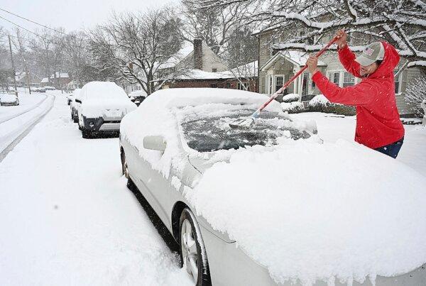 Christian Lively sweeps snow off his car in front of his house on Woodlawn Ave in Beckley, W.Va., on Feb. 11, 2025. (Rick Barbero/The Register-Herald via AP)