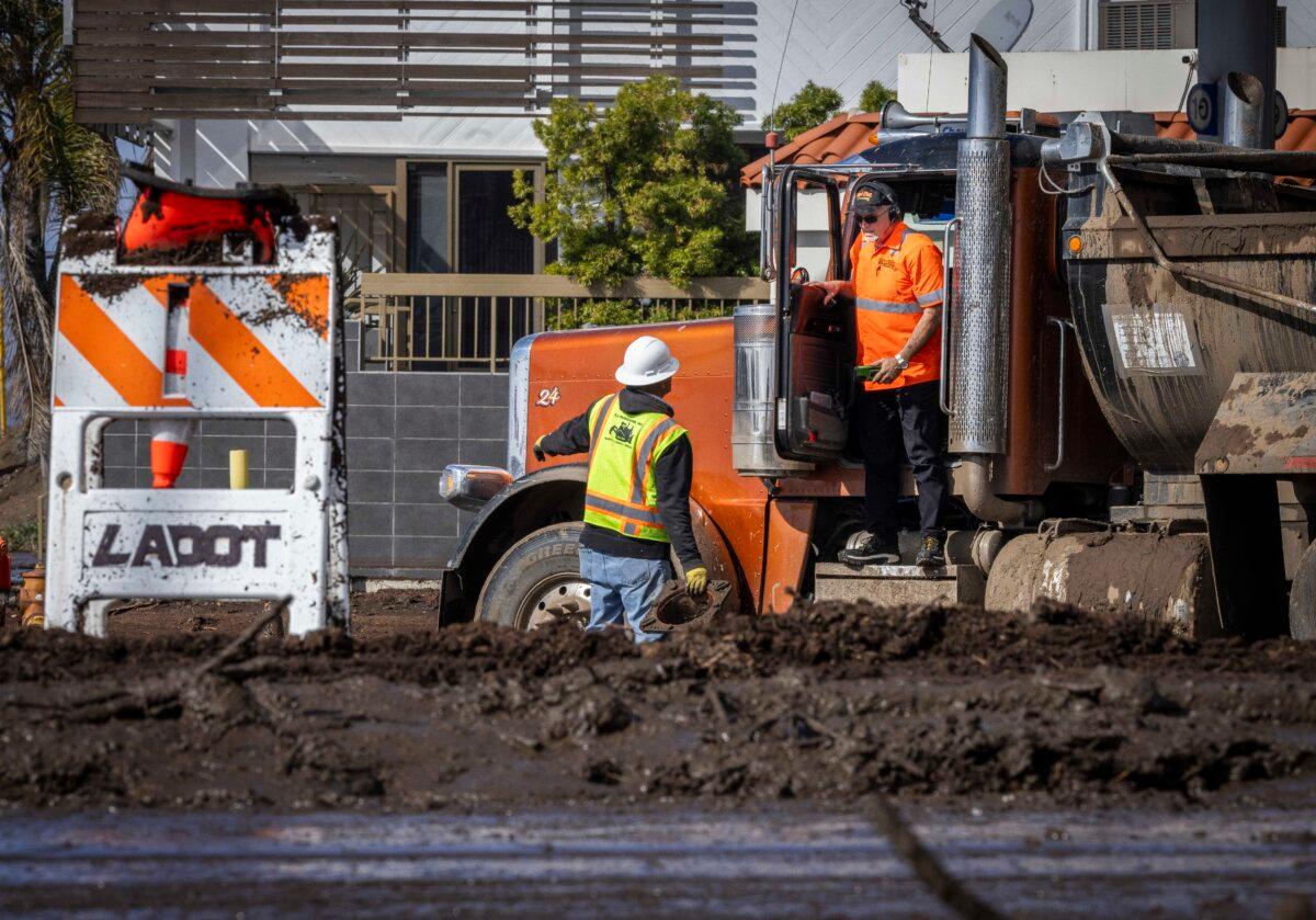 First responders and clean-up crews work to clear mud and debris flows left over from the Palisades Fire caused by heavy rains along Pacific Coast Highway near Los Angeles on Feb. 14, 2024. (John Fredricks/The Epoch Times)