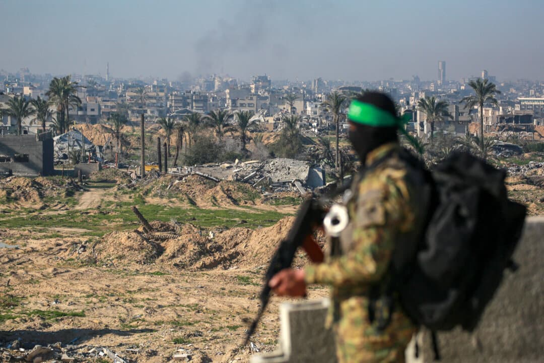 A Hamas fighter stands guard on the rooftop of a building overlooking an area secured by fellow terrorists in Khan Yunis in the southern Gaza Strip, before the release of three Israeli hostages on Feb. 15, 2025, as part of the sixth hostage-prisoner exchange in exchange for 369 Palestinians in Israeli custody. (Bashar Taleb/AFP via Getty Images)