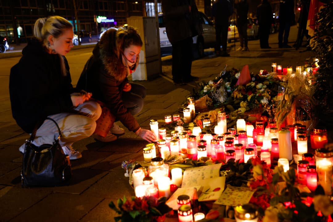 People place a candle in tribute to victims at the makeshift memorial set up at the scene where an Afghan asylum seeker, who was granted a Munich residence permit, drove a car into a crowd in Munich, Germany, on Feb. 15, 2025. A 2-year-old girl and her mother died as a result, and 37 others were injured, police said, noting the attacker showed