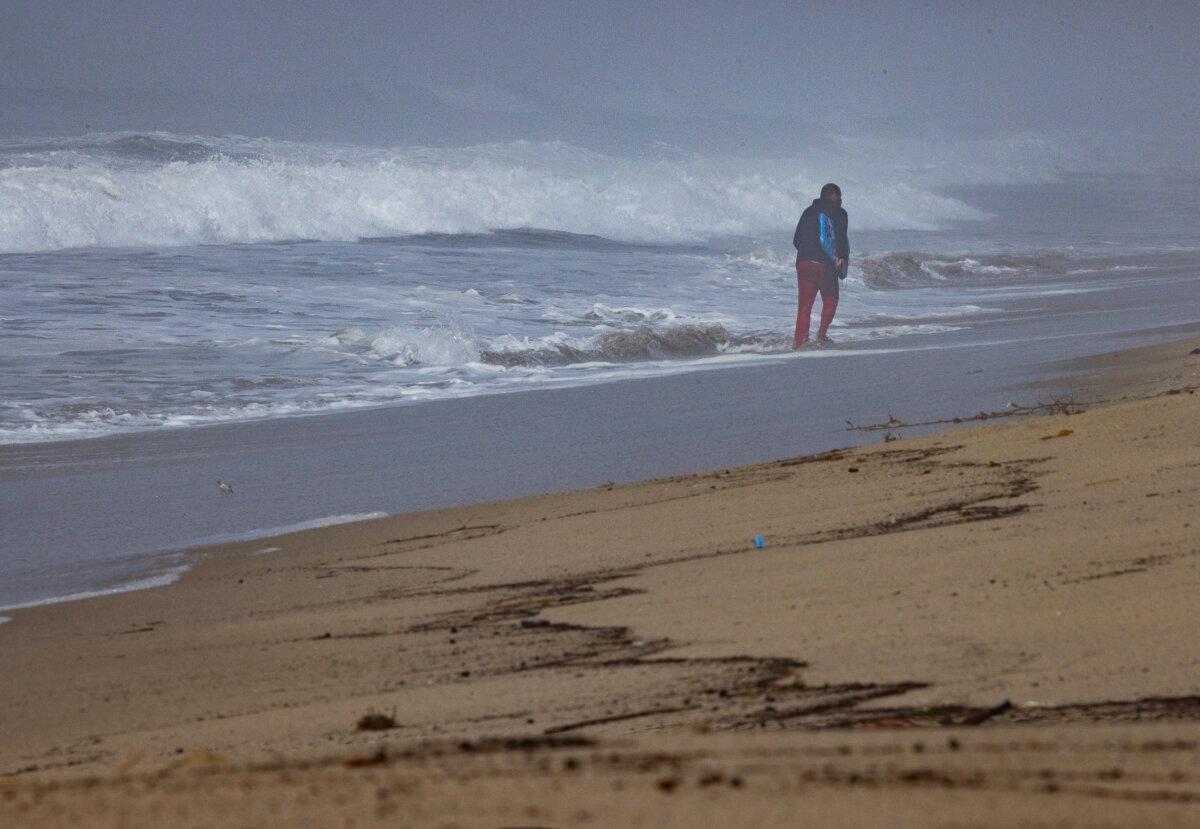 A man walks among debris leftover from the Palisades fire and heavy rains near Los Angeles, on Feb. 27, 2025. (John Fredricks/The Epoch Times)