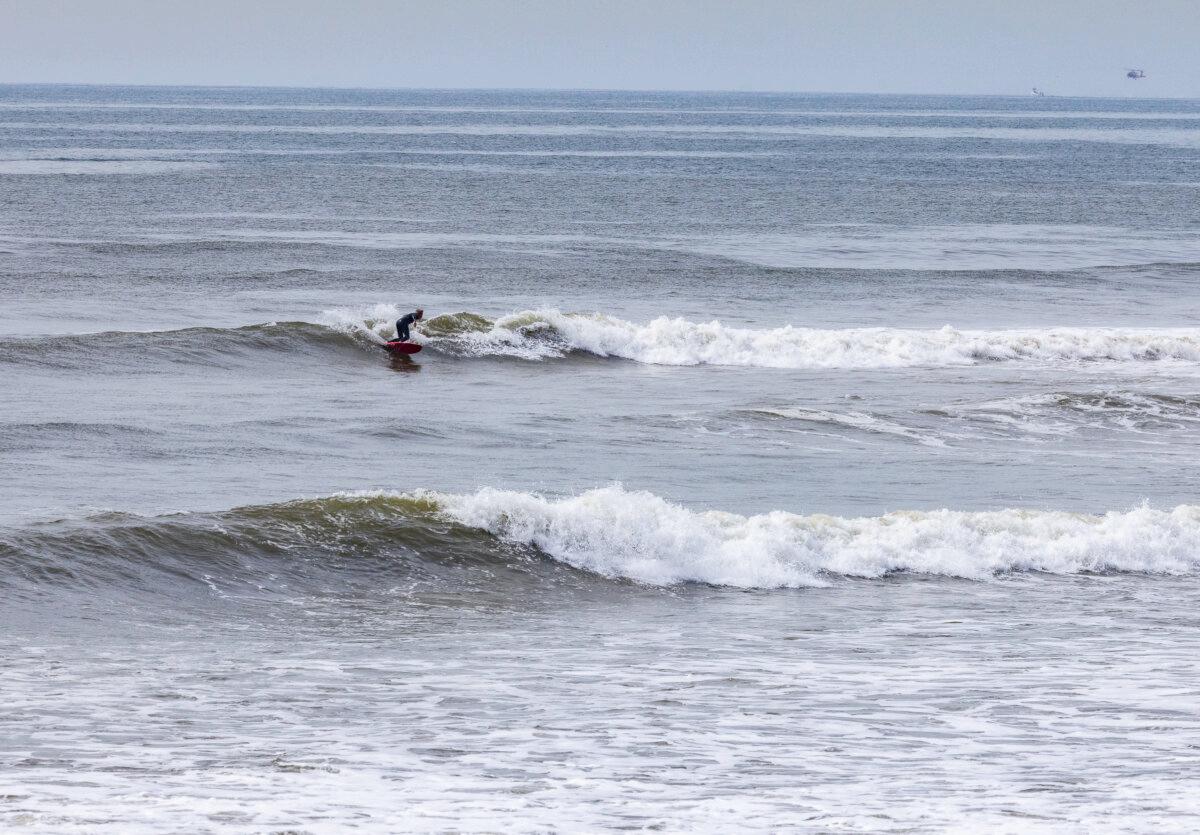 A man surfs amongst debris leftover from the Palisades fire and heavy rains near Los Angeles, on Feb. 27, 2025. (John Fredricks/The Epoch Times)