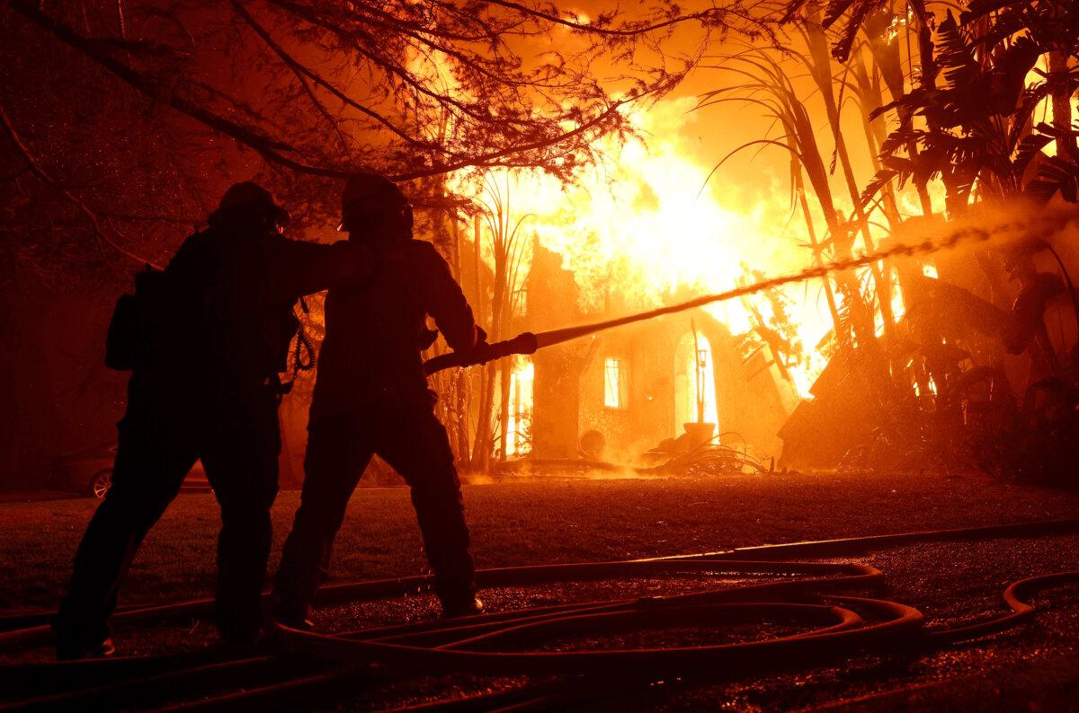 Los Angeles County firefighters spray water on a burning home as the Eaton Fire moves through the area in Altadena, Calif., on Jan. 8, 2025. (Justin Sullivan/Getty Images)
