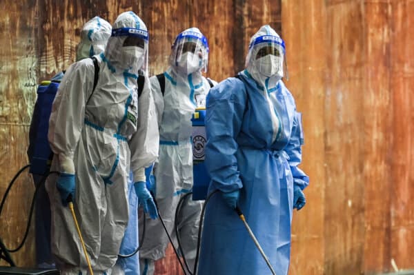 Workers who handle disinfectant look on next to a residential area under a COVID-19 lockdown in the Huangpu district of Shanghai on June 4, 2022. (Hector Retamal/AFP via Getty Images)