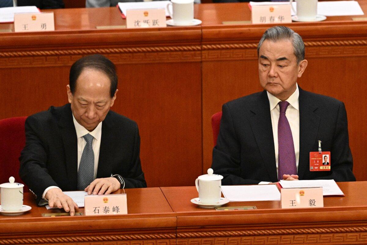 CCP's Central Committee Political Bureau member Shi Taifeng (L) votes next to Foreign Minister Wang Yi during the closing session of China's rubber-stamp legislature, the National People's Congress, in Beijing on March 11, 2025. (Pedro Pardo/AFP via Getty Images)