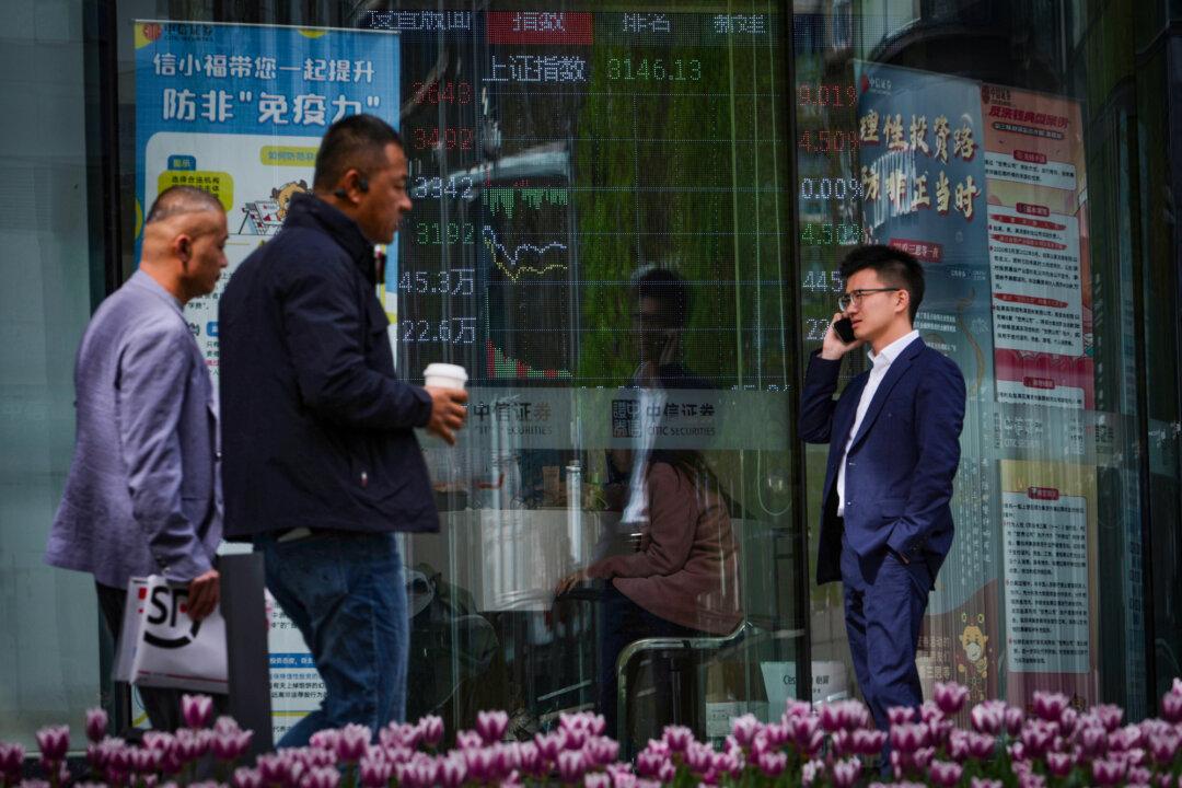 People walk past an electronic board displaying Shanghai shares trading index at a brokerage house in Beijing on April 7, 2025. (Andy Wong/AP Photo)