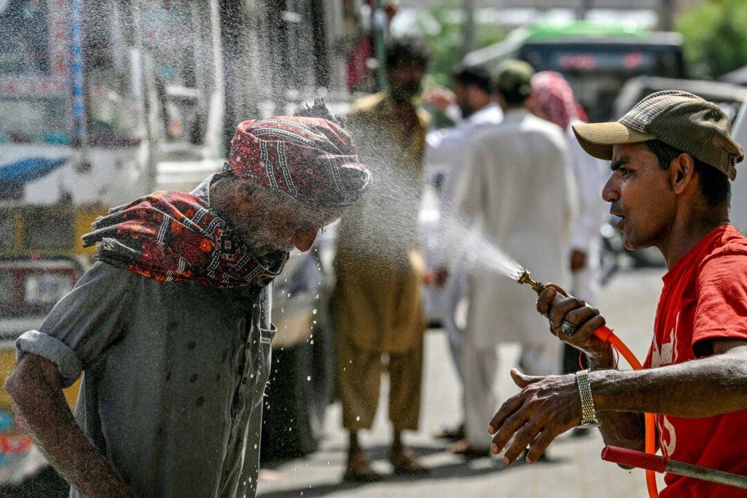 A volunteer of the Edhi Foundation sprays water on a passerby's head to cool off along a road amid an ongoing heatwave in Karachi, Pakistan, on April 21, 2025. (Asif Hassan/AFP via Getty Images)