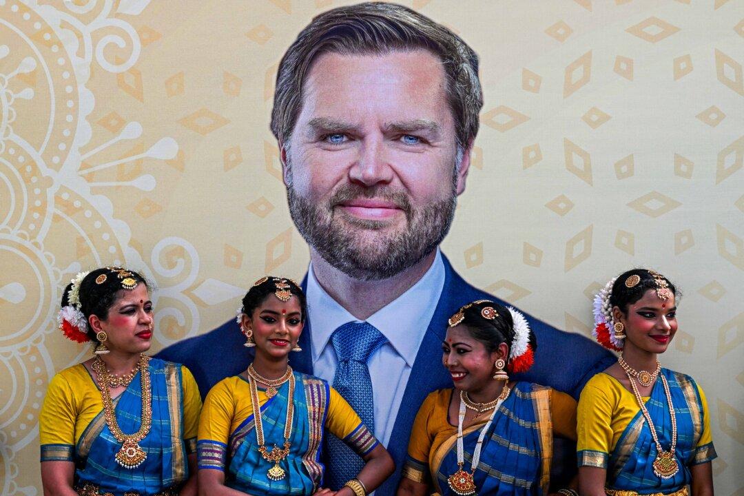 Dancers wearing traditional attire stand in front of a poster depicting U.S. Vice President JD Vance upon his arrival in New Delhi on April 21, 2025. Vance begins a four-day visit to India as New Delhi looks to seal an early trade deal and stave off U.S. tariffs. His tour includes a meeting with Indian Prime Minister Narendra Modi in New Delhi. (Kenny Holston/Pool/AFP via Getty Images)