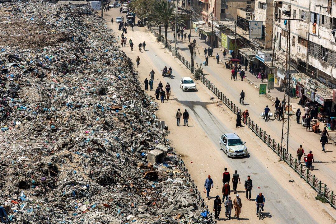 People walk along the street past the former site of the Firas Market, which has been transformed into a landfill during the Israeli–Hamas war, in Gaza City on April 21, 2025. (Omar Al-Qattaa/AFP via Getty Images)
