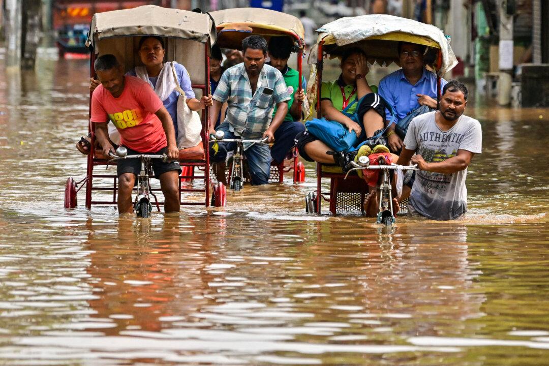 Rickshaw drivers wade through a flooded street after heavy rains in Guwahati, India, on April 22, 2025. (Biju Boro/AFP via Getty Images)