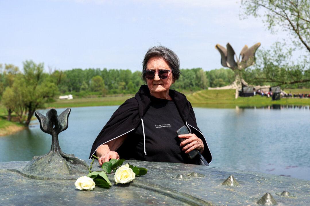 A woman lays a white rose during a ceremony at the Stone Flower monument in honor of tens of thousands of ethnic Serbs, Jews, and others who were killed in the Jasenovac concentration camp during World War II, in Croatia, on April 22, 2025. A memorial is held at the death camp site each year on the anniversary of the last attempted break-out by inmates on April 22, 1945. (Damir Sencar/AFP via Getty Images)