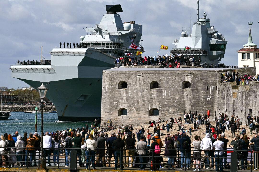 Onlookers gather at the Round Tower to watch British aircraft carrier HMS Prince of Wales leave from Portsmouth Naval Base on the southern coast of England, for deployment to the Indo-Pacific region, on April 22, 2025. (Ben Stansall/AFP via Getty Images)