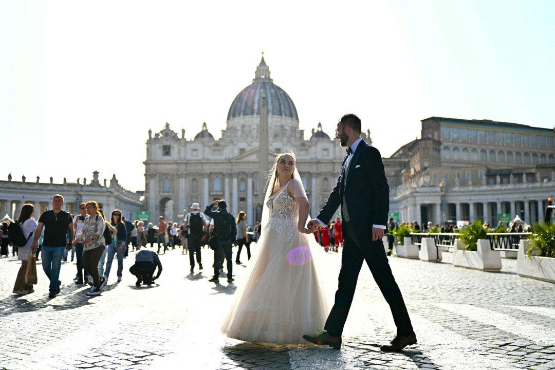 Newlyweds stroll in the Vatican's St. Peter's square a day after Pope Francis's death, in Rome on April 22, 2025. The 88-year-old pontiff died of a stroke on April 21, after 12 years leading the Catholic Church. (Alberto Pizzoli/AFP via Getty Images)