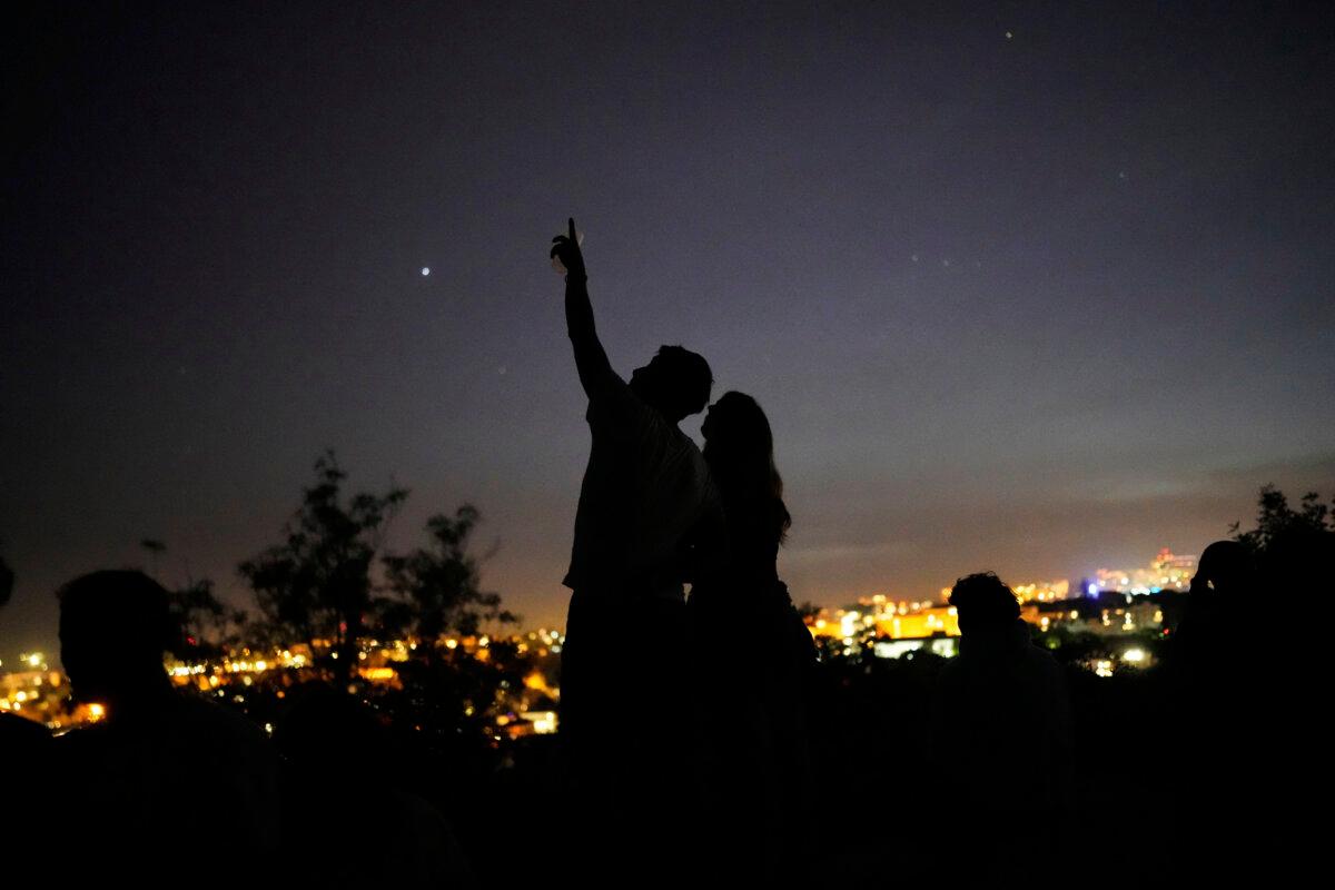 A young couple stands on a wall looking at the sky at a viewpoint overlooking Lisbon, Portugal, during a nationwide power outage, dated April 28, 2025. (Armando Franca/AP Photo)