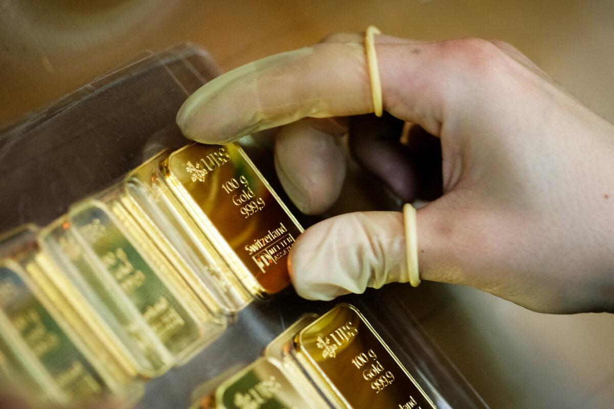 An employee wears gloves while holding a 100g gold bar, engraved with the logo and name of the Swiss bank UBS, at a plant of gold refiner and bar manufacturer Argor-Heraeus SA in Mendrisio, southern Switzerland, on April 6, 2009. (AFP/Sebastian Derungs)