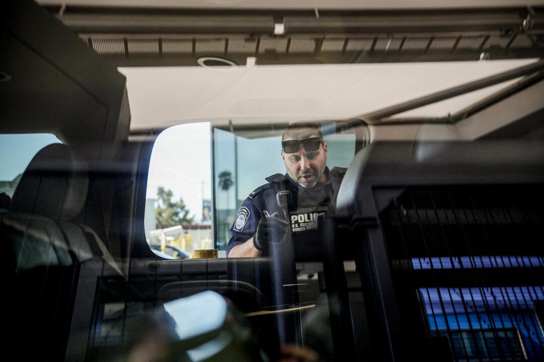A U.S. Customs and Border Protection agent checks a vehicle for contraband in the line to enter the United States at the San Ysidro Port of Entry in San Ysidro, Calif., on Oct. 2, 2019. Yuan Hongbing, a former Peking University law professor, said the Chinese Communist Party has for years pushed fentanyl into the United States—under a plan the regime dubbed Project Zero—to fuel drug addiction among Americans. (Sandy Huffaker/AFP via Getty Images)